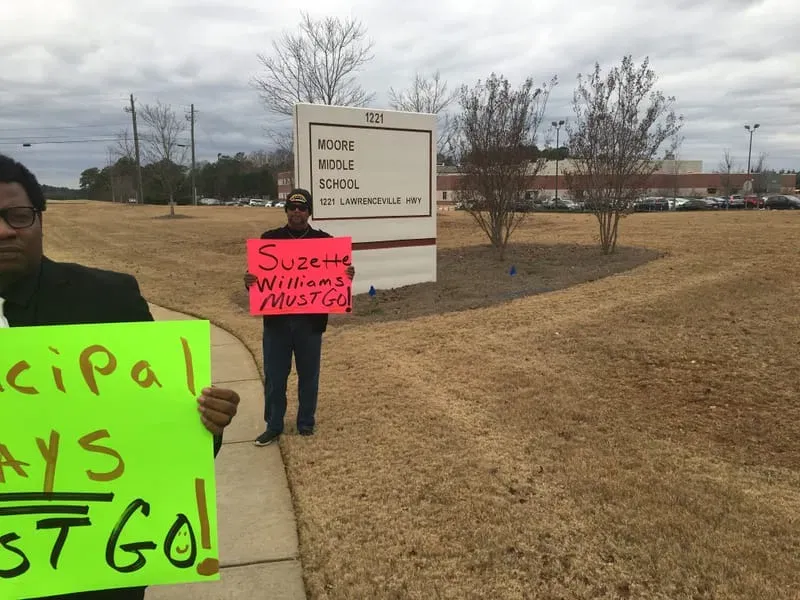 A.P.E. advocates holding signs outside a school